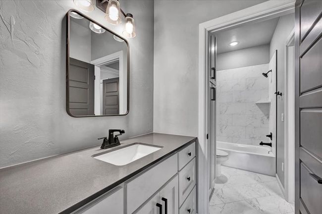 Bathroom featuring marble finish floors, vanity, toilet, shower combination, and a textured wall | Image 44