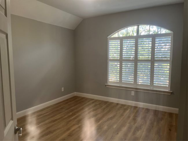 Unfurnished room featuring healthy amount of natural light, wood finished floors, and vaulted ceiling | Image 13