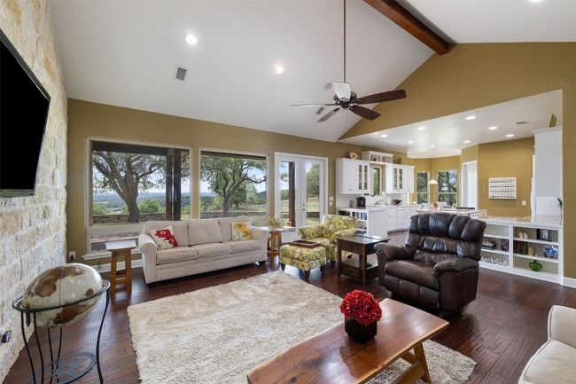 Living area featuring high vaulted ceiling, ceiling fan, beam ceiling, and dark wood-type flooring | Image 17
