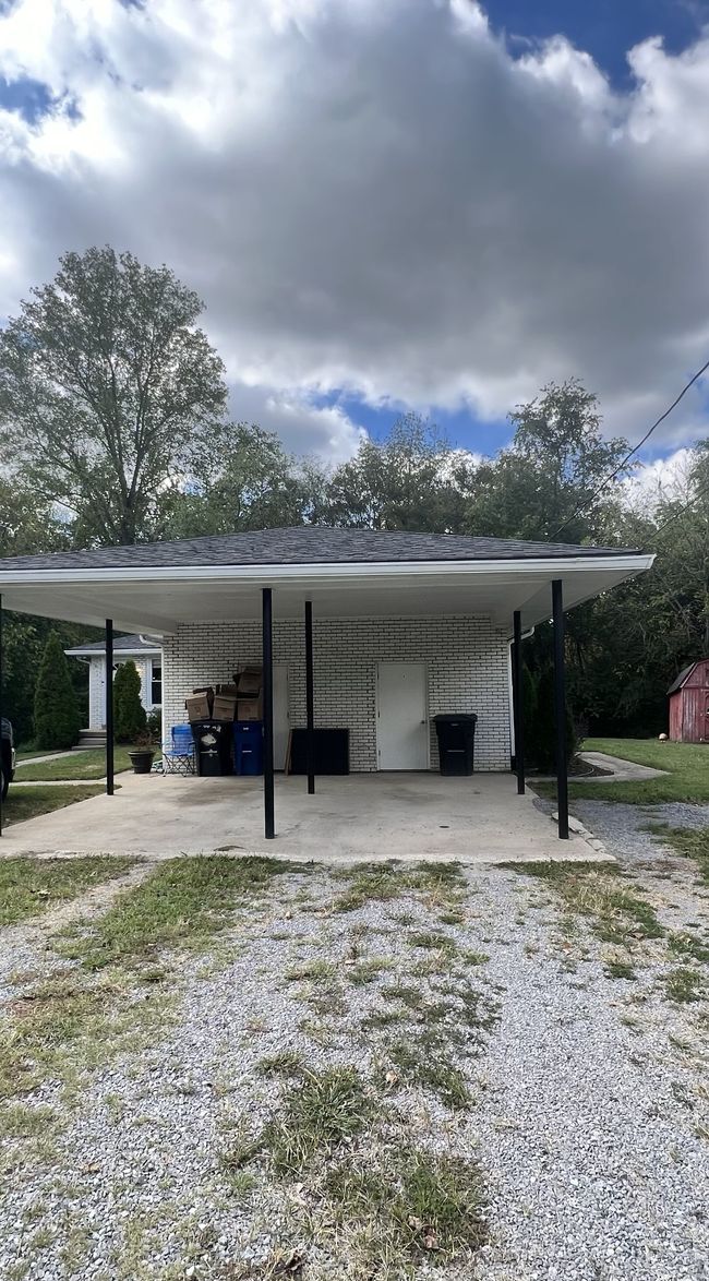 A gravel driveway with covered carport and storage closet. | Image 15