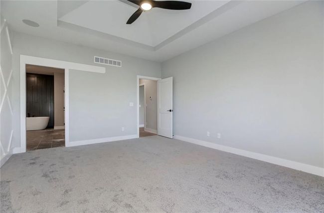 Unfurnished bedroom featuring carpet flooring, a raised ceiling, baseboards, and ceiling fan | Image 10