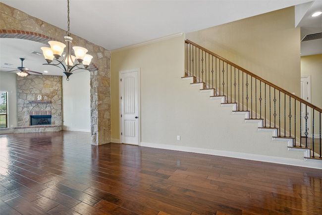 Unfurnished living room with a ceiling fan, a chandelier, wood finished floors, and stairway | Image 12