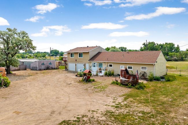 Rear view of property with driveway, a garage, fence, and a shingled roof | Image 88