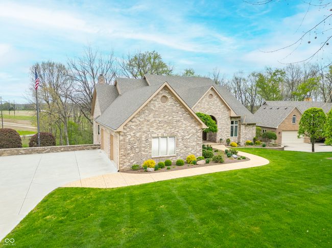 view of front of house featuring a chimney, a shingled roof, a garage, driveway, and a front yard | Image 109