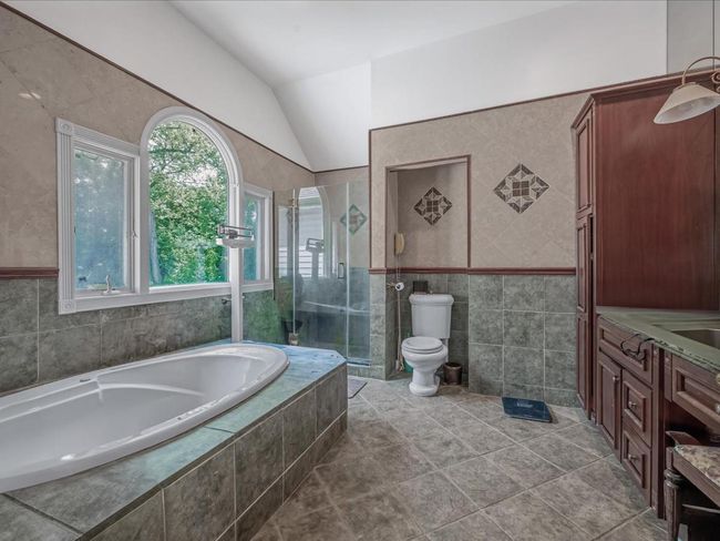 Full bath featuring tile walls, a bath, lofted ceiling, a stall shower, and toilet | Image 19