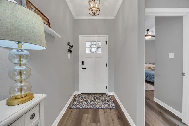 Foyer entrance featuring baseboards, wood finished floors, a notable chandelier, and ornamental molding | Image 4
