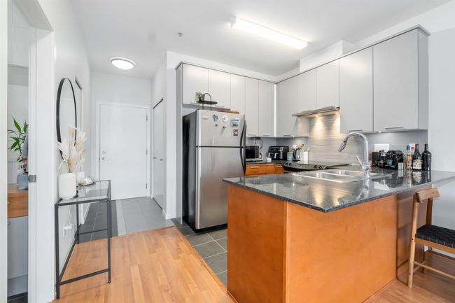 Kitchen featuring decorative backsplash, dark stone countertops, freestanding refrigerator, a peninsula, and a sink | Image 16