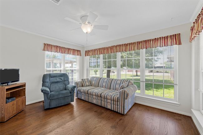 Living area with wood finished floors, crown molding, baseboards, and a ceiling fan | Image 25