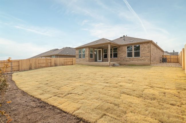 Rear view of property with central air condition unit, brick siding, a fenced backyard, and a shingled roof | Image 16