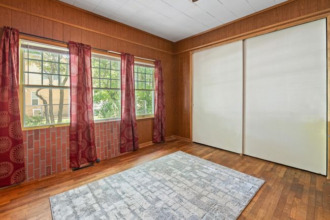 Unfurnished bedroom featuring wood finished floors, wood walls, and a closet | Image 15