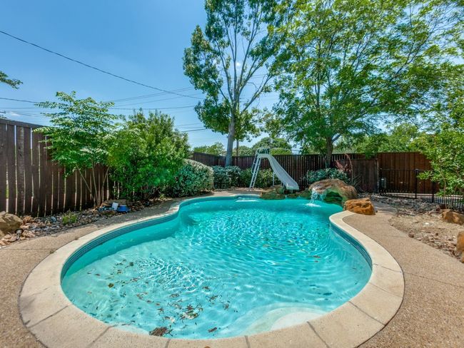 View of pool with a water slide and a fenced backyard | Image 23