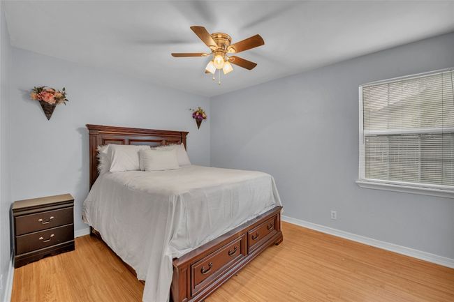 Bedroom with light wood-type flooring, baseboards, and ceiling fan | Image 14
