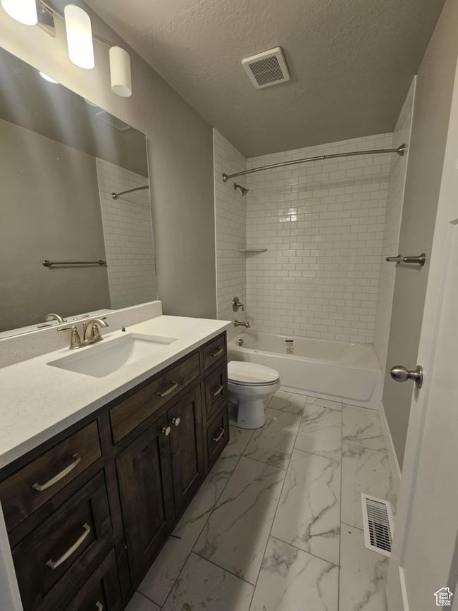 Full bathroom with marble finish flooring, vanity, shower / bath combination, toilet, and a textured ceiling | Image 9