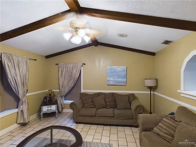 Living room featuring light tile floors, a textured ceiling, ceiling fan, and lofted ceiling with beams | Image 6