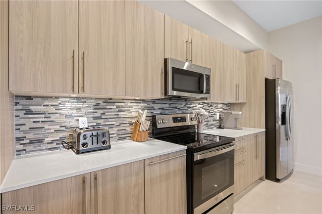 Kitchen featuring backsplash, appliances with stainless steel finishes, light brown cabinets, and modern cabinets | Image 14