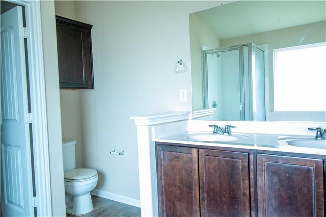 Bathroom with a stall shower, double vanity, and wood finished floors | Image 8