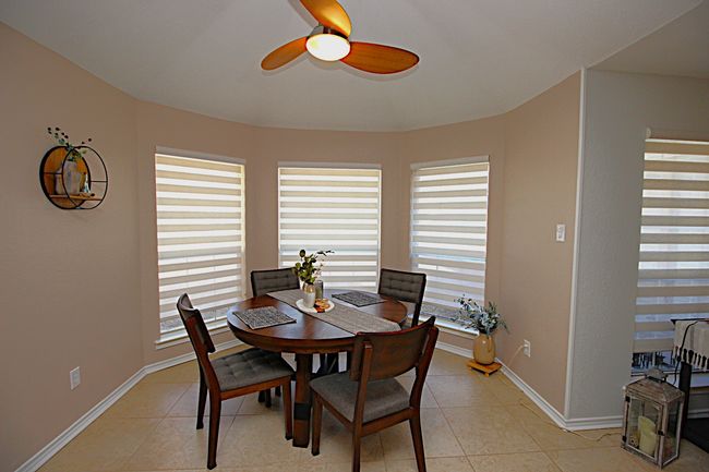 Dining room with light tile patterned floors, baseboards, new roman shades and a ceiling fan | Image 16