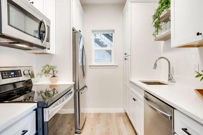 Kitchen featuring sink, light hardwood / wood-style floors, white cabinetry, and appliances with stainless steel finishes | Image 6