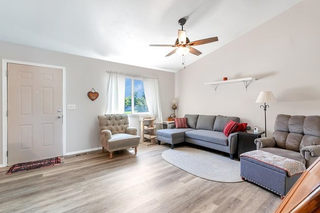 Living area featuring light wood-type flooring, ceiling fan, and vaulted ceiling | Image 10