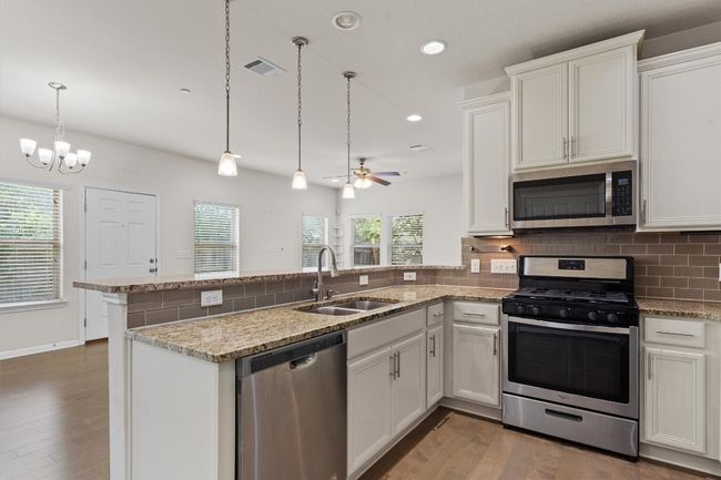 Kitchen featuring appliances with stainless steel finishes, a sink, a peninsula, wood finished floors, and recessed lighting | Image 11