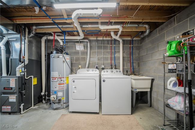 Basement featuring separate washer and dryer, gas water heater, and sink | Image 19