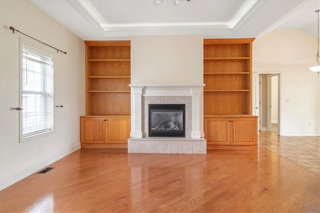 Unfurnished living room featuring visible vents, built in features, light wood finished floors, and a tile fireplace | Image 11