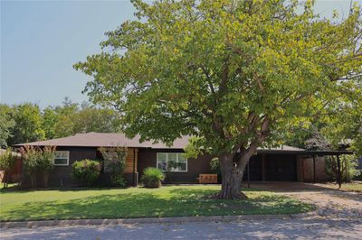 View of front facade with a front lawn, a carport, and a garage | Image 1