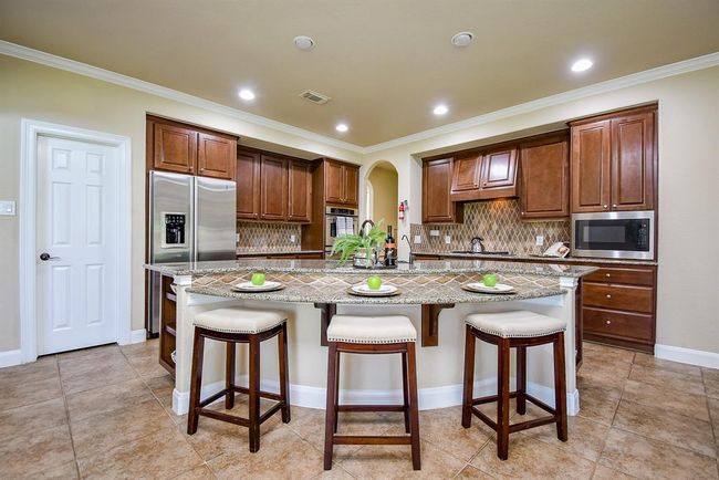 A spacious island with bar seating defines this kitchen, featuring lower cabinetry and cleverly integrated open shelving. This is a space equally suited to weekday breakfasts and festive weekend cooking. | Image 13