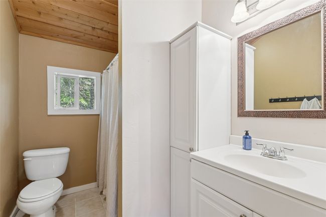 Apartment bathroom with tile patterned floors, wooden ceiling, and vanity | Image 48