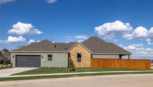 View of front of home featuring concrete driveway, roof with shingles, an attached garage, stone siding, and brick siding | Image 32
