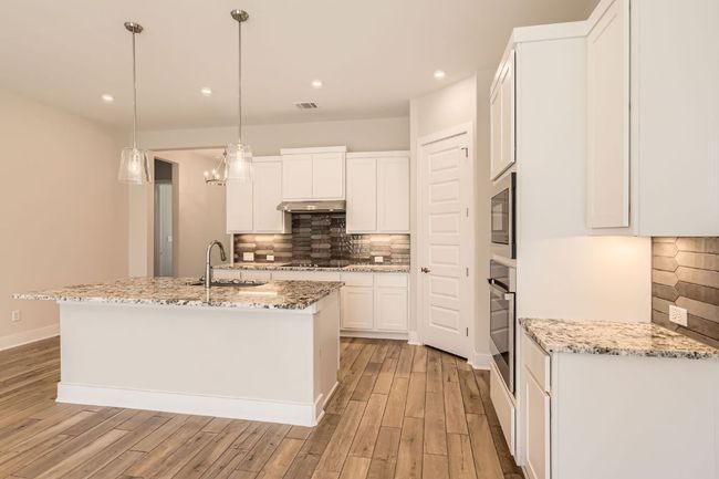 Kitchen with black electric cooktop, tasteful backsplash, light wood-style floors, and oven | Image 14