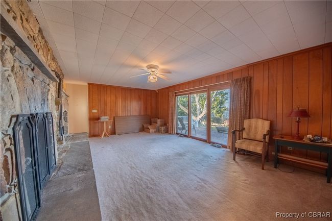 Living room with ornamental molding, a fireplace, carpet, and wood walls | Image 10