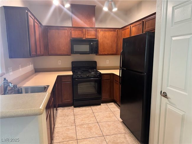 Kitchen with black appliances, light tile patterned floors, and light countertops | Image 7