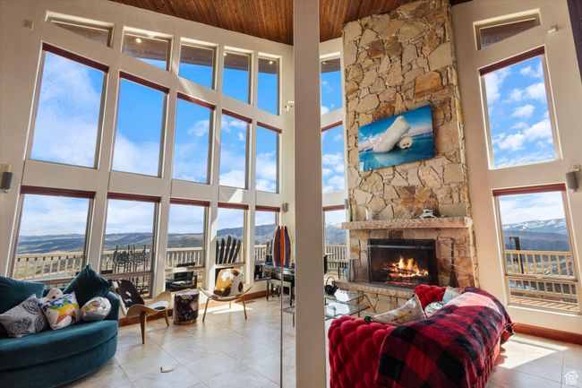 Tiled living area with a stone fireplace, a high ceiling, wood ceiling, and a mountain view | Image 4