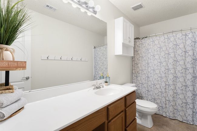 This upstairs bathroom features newly painted walls, a large vanity, and a tub with a shower. | Image 28