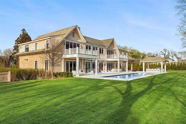 Rear view of property featuring a patio, yard, balconies, covered areas, pool, spa, outdoor kitchen & putting green | Image 39