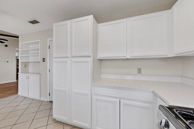 Kitchen with stainless steel range, white cabinets, and light tile patterned floors | Image 12
