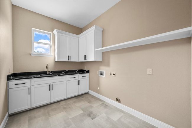 Laundry room featuring washer hookup, cabinet space, hookup for an electric dryer, a sink, and baseboards | Image 32