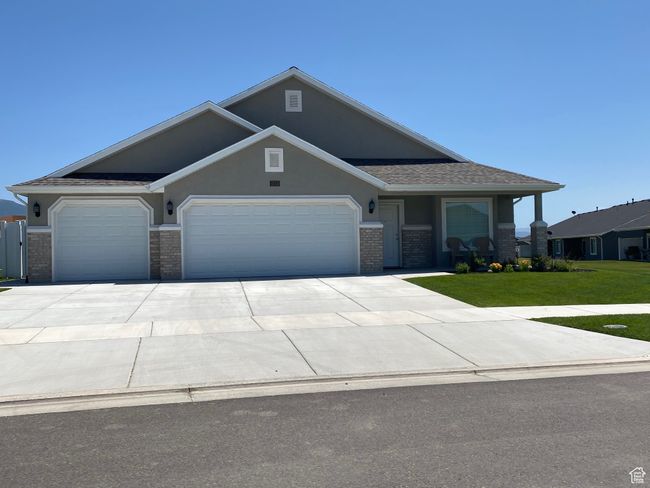 View of front of house with a front lawn, concrete driveway, a garage, brick siding, and stucco siding | Image 4