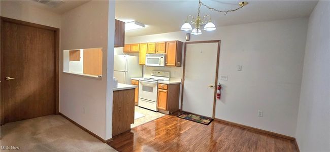 Kitchen with white appliances, a chandelier, light countertops, and baseboards | Image 11