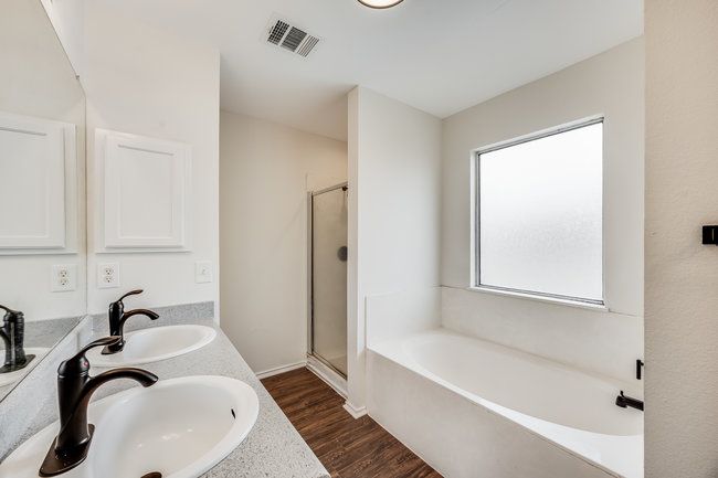 Full bath featuring a bath, a stall shower, double vanity, and wood finished floors | Image 32