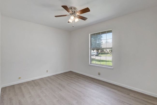 Spare room with wood finished floors, baseboards, and a ceiling fan | Image 15