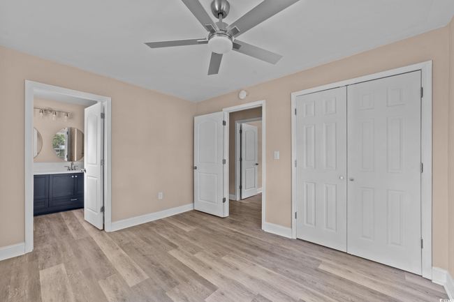 Unfurnished bedroom featuring light wood finished floors, a closet, ensuite bath, and a ceiling fan | Image 34