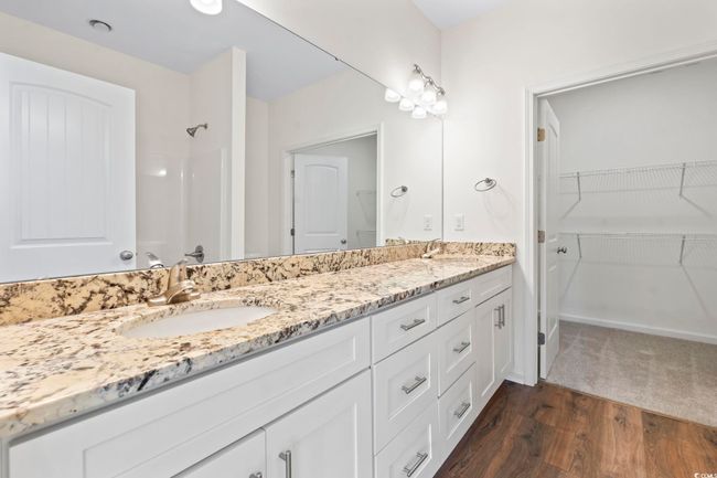 Full bath featuring double vanity, wood finished floors, a shower, and a walk in closet | Image 19