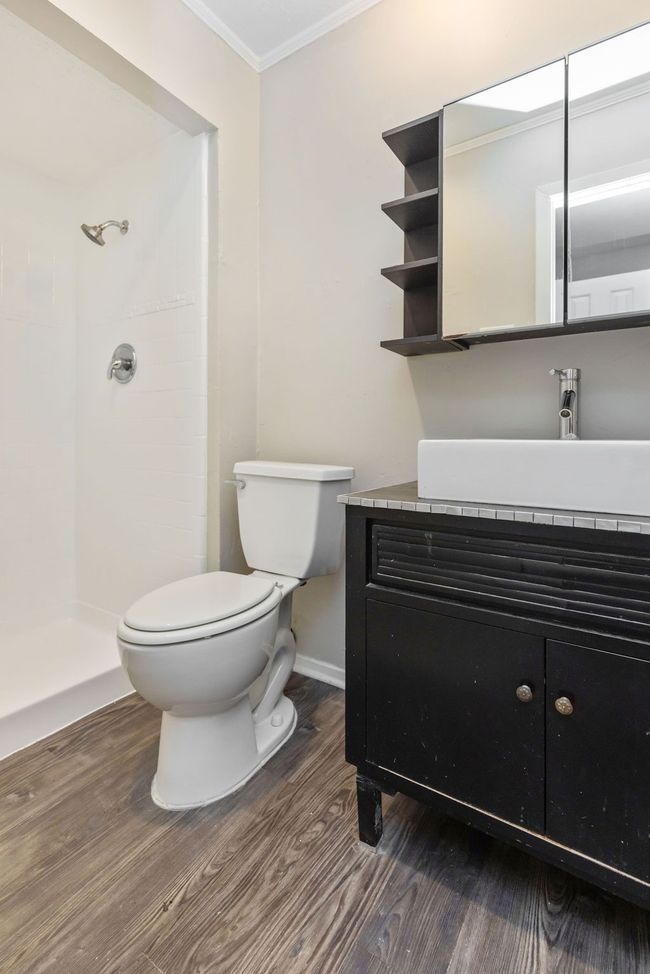Bathroom featuring vanity, toilet, ornamental molding, tiled shower, and wood finished floors | Image 28