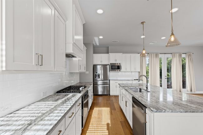 Kitchen with stainless steel appliances, a sink, white cabinets, light wood finished floors, and recessed lighting | Image 5