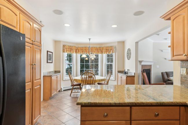 Kitchen with black fridge, decorative light fixtures, light stone counters, and kitchen peninsula | Image 8