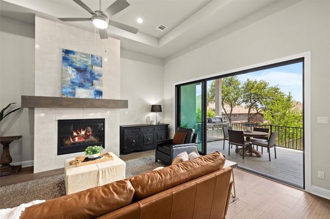 Living area with ceiling fan, a tile fireplace, a towering ceiling, wood finished floors, and recessed lighting | Image 11