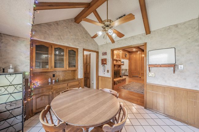 Dining room featuring wainscoting, a ceiling fan, light tile patterned floors, and wood walls | Image 8