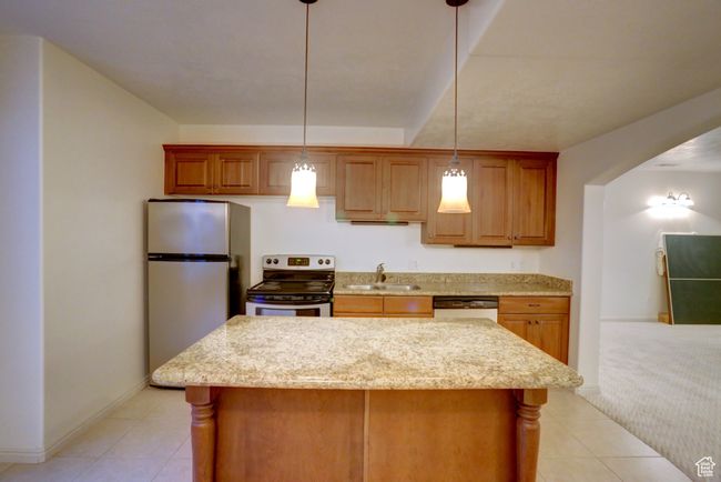 Kitchen featuring a center island, light tile patterned floors, a sink, and stainless steel appliances | Image 38